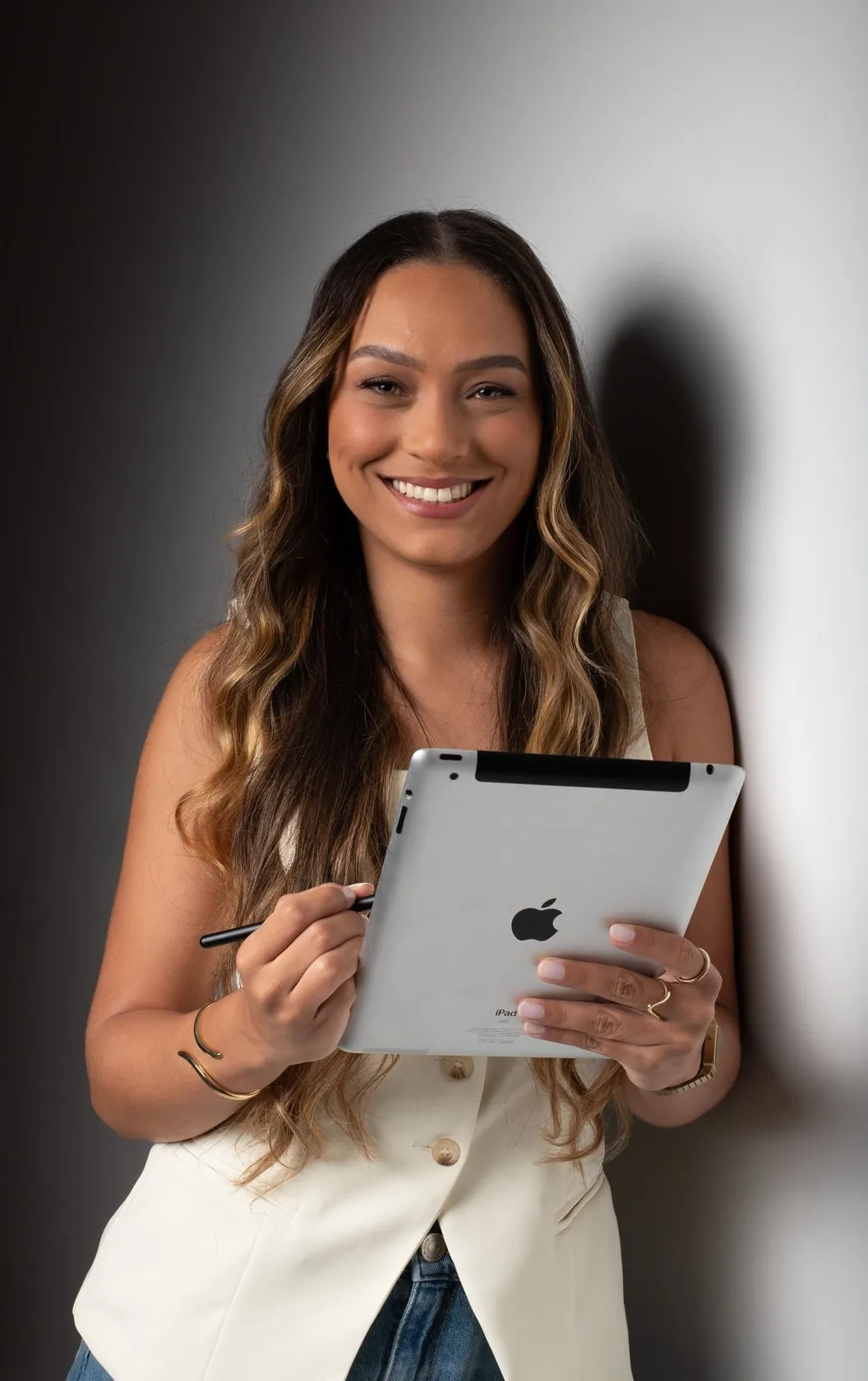 Mulher sorrindo, segurando um tablet e uma caneta digital.