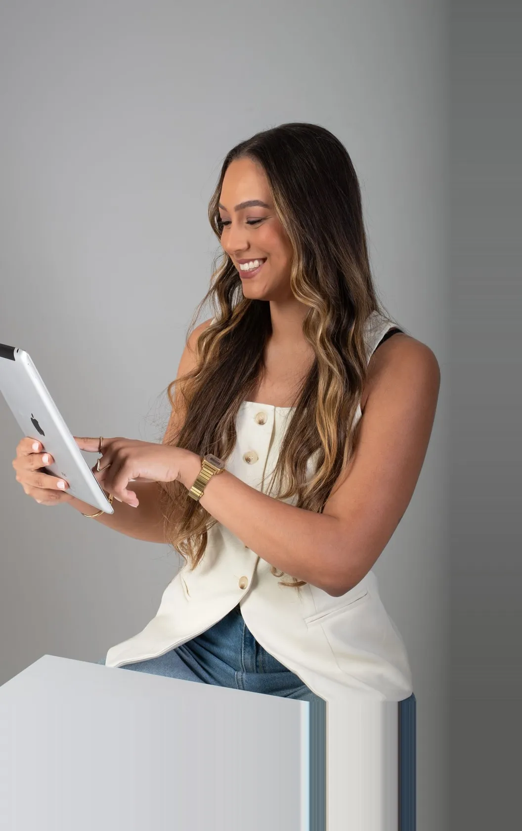 Mulher sorrindo enquanto usa um tablet, em pé.