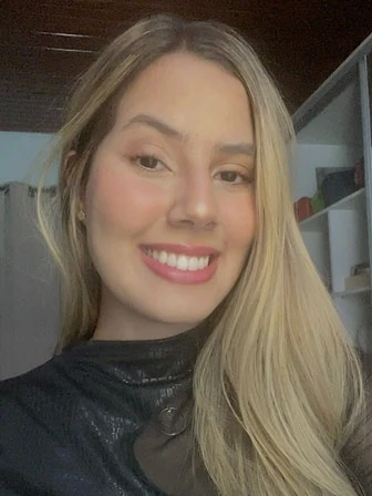 Letycia, de cabelos longos loiros e blusa preta, sorrindo em uma selfie.